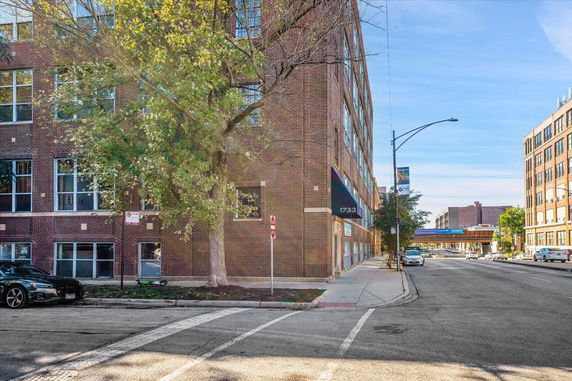 Front view of a brick multi-story building on a city street.