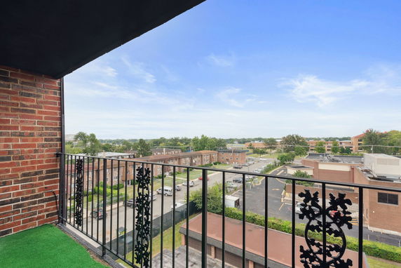 View from a balcony overlooking buildings and parking area.