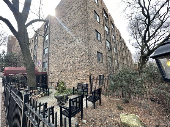 Front view of a multi-story brick building with an entrance canopy and outdoor seating area.