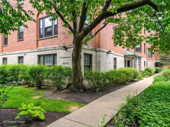 Front view of a brick residential building with multiple windows and a small entrance porch.