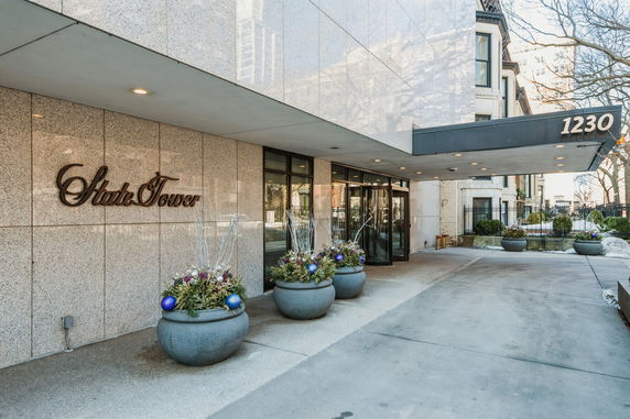 Front view of a building entrance with a canopy and decorative planters.