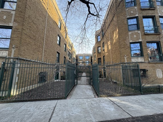 Front view of a multi-story brick building with gated entrance