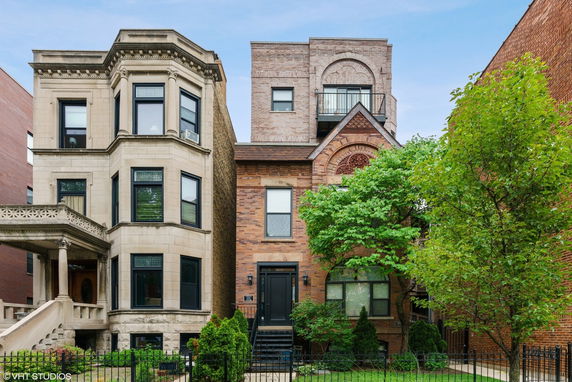 Front view of a two-story brick house with a detailed facade and adjacent masonry building.