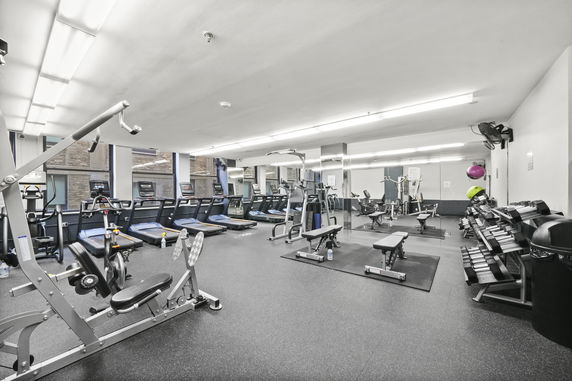 Interior view of a gym with various exercise equipment including treadmills and weight benches.