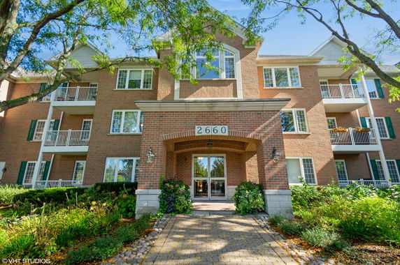 Front view of a multi-story brick apartment building with balconies and a central entrance.