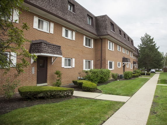 Front view of a multi-story brick apartment building with gable roof extensions.
