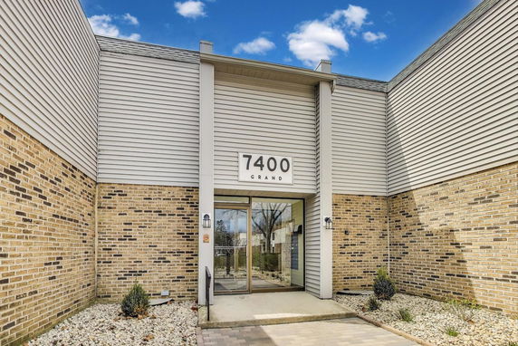 Front view of a building entrance with a brick and siding exterior.