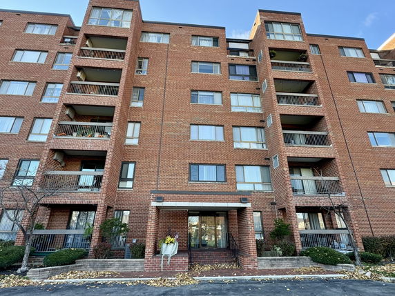 Front view of a multi-story brick apartment building with balconies.