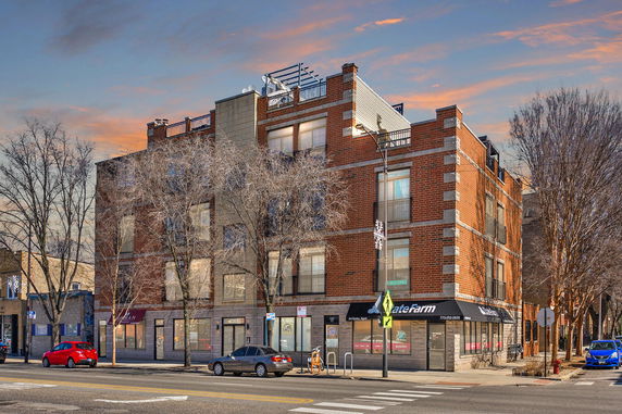 Front view of a multi-story brick building on a street corner.