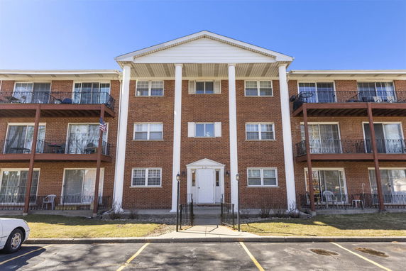 Front view of a three-story apartment building with brick exterior and balconies.