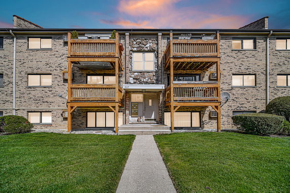 Front view of a multi-story brick apartment building with wooden balconies.