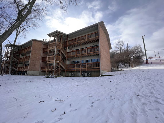 Side view of a three-story brick building with wooden balconies in a snowy landscape.
