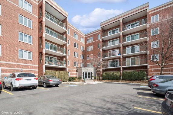 View of a multi-story brick building with a parking area in front.