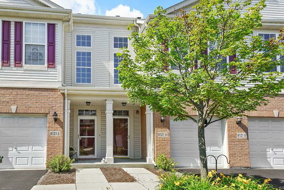 Front view of a two-story townhouse with garage and entrance flanked by columns.