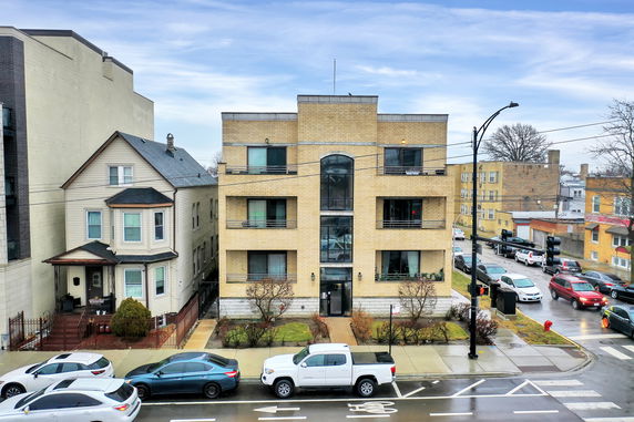 Front view of a multi-story brick building with large windows and balconies.