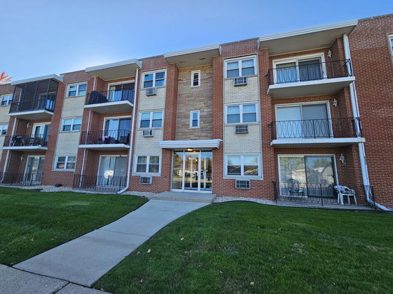 Front view of a multi-story brick apartment building with balconies.
