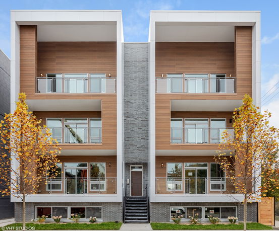 Front view of a modern multi-story residential building with wood paneling and balconies.