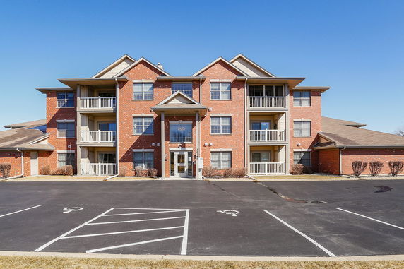 Front view of a three-story brick apartment building with balconies and a central entrance.