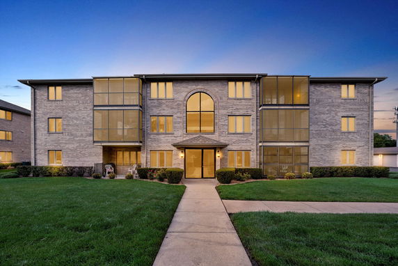 Front view of a three-story brick apartment building with large windows and a central entrance.