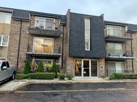 Front view of a multi-story brick apartment building with balconies.