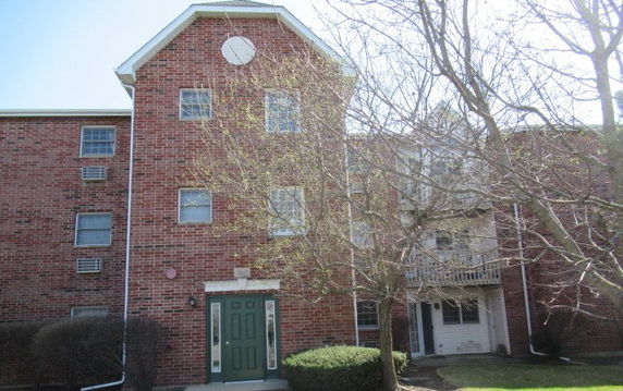 Front view of a three-story brick building with a green door.