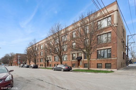 Front view of a multi-story brick building on a street corner.