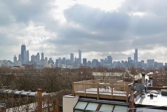 Skyline view of a city with tall buildings seen from a rooftop.