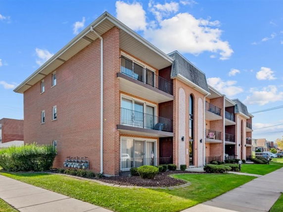 Front view of a multi-story apartment building with brick exterior and balconies.