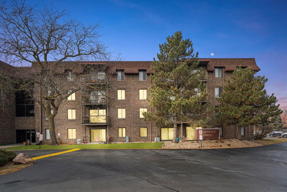Front view of a multi-story brick building with a sloped roof and balconies.