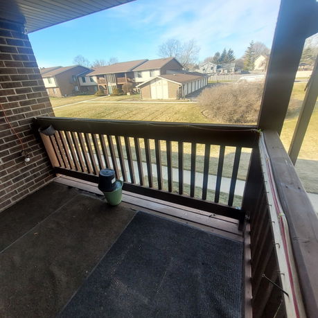 View from a balcony overlooking residential houses and a grassy area.