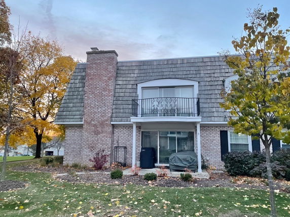 Front view of a two-story house with a chimney and balcony.
