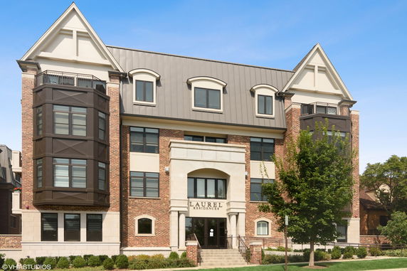 Front view of a multi-story brick building with large windows and dormer roofs.