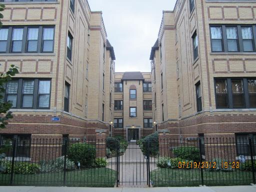 Front view of a multi-story apartment building with courtyard entrance.