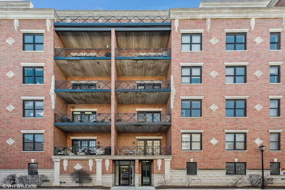 Front view of a multi-story brick apartment building with balconies.