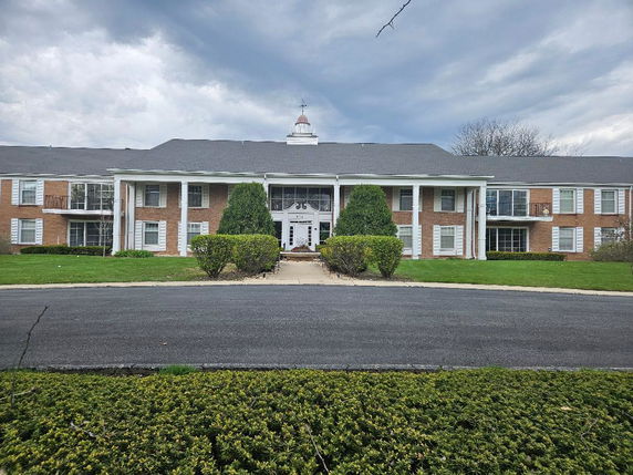 Front view of a two-story brick building with white columns and large windows.
