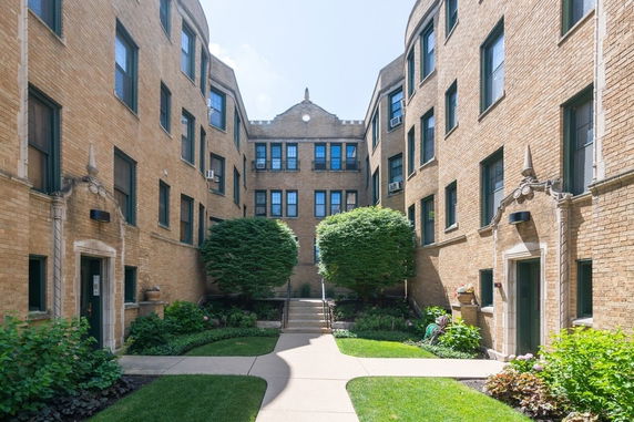 Front view of a brick apartment building with multiple windows and entrances.