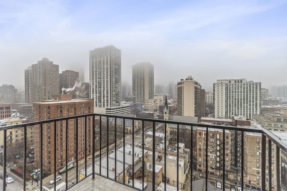 Panoramic view of a cityscape with tall buildings and a foggy sky seen from a balcony.
