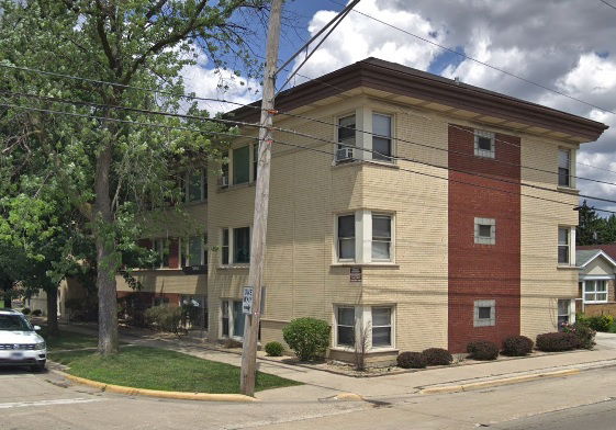Front view of a three-story brick apartment building with a combination of tan and red bricks.