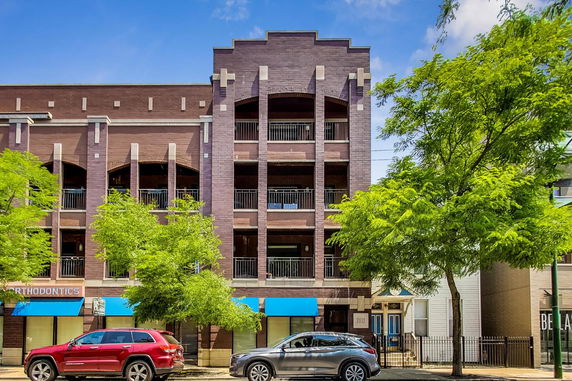 Front view of a multi-story building with balconies and commercial space on the ground floor.