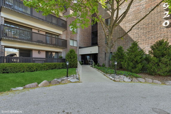 Front view of a multi-story brick building with balconies and entrance path.