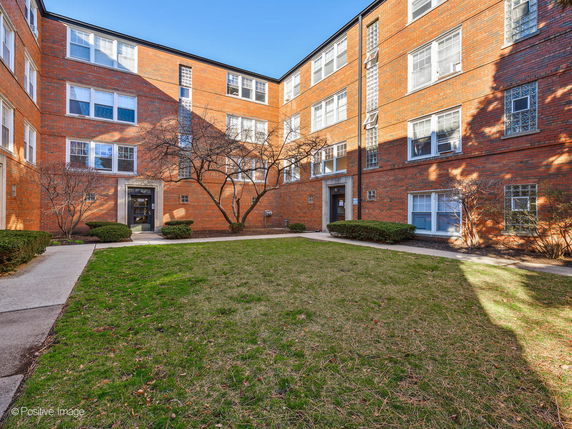 Front view of a multi-story brick apartment building with large windows.
