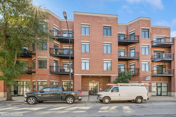Front view of a multi-story apartment building with red brick exterior and balconies.