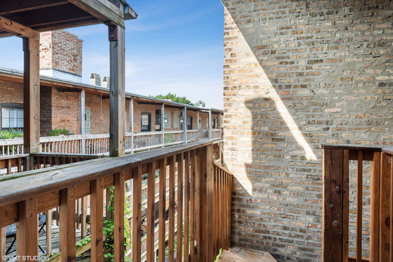 View from a wooden balcony with brick buildings and railings.