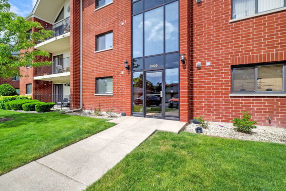 Front view of a multi-story brick apartment building with balconies.