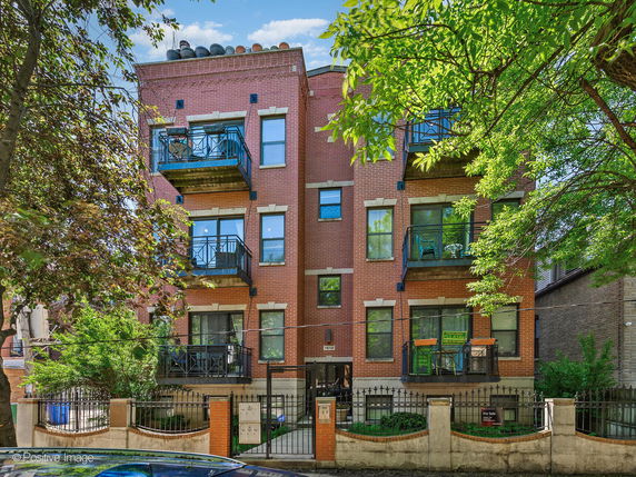 Front view of a multi-story brick apartment building with balconies.