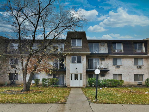 Front view of a three-story residential building with balconies and a central entrance.