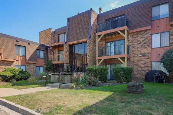 Front view of a multi-story brick apartment building with balconies.