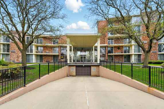 Front view of a multi-story brick building with balconies and a central entrance.