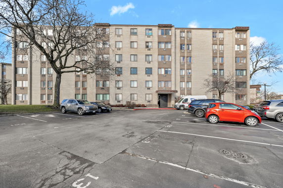 Front view of a multi-story apartment building with a parking area in front.