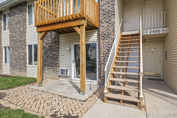 Front view of a multi-story building with a wooden staircase and balcony.